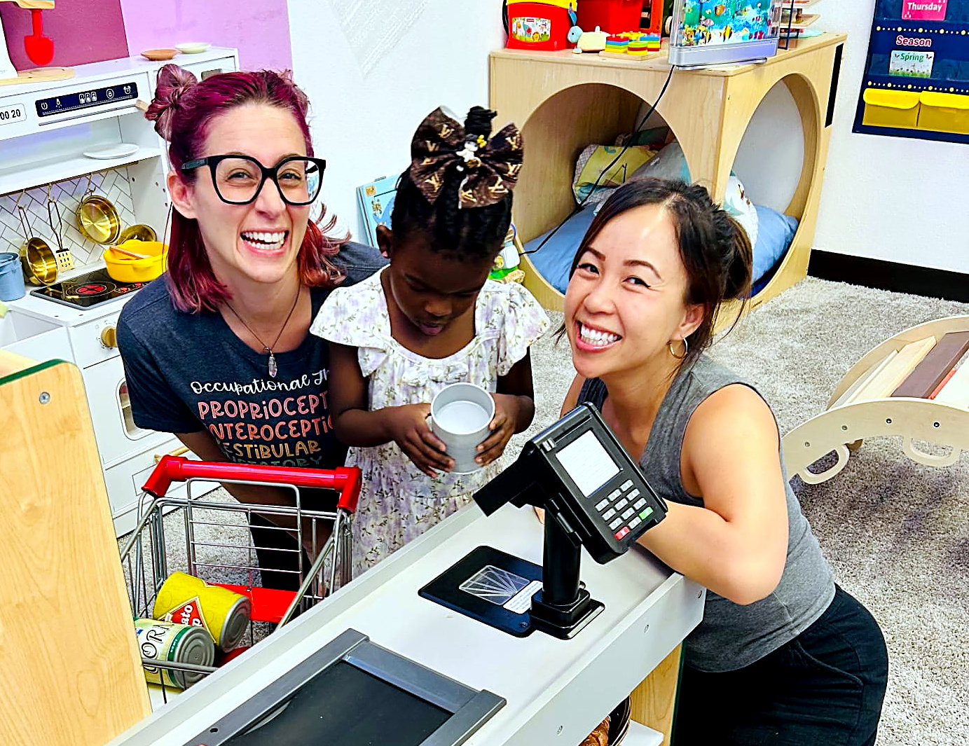 Danielle and My smiling with a child during play-based therapy